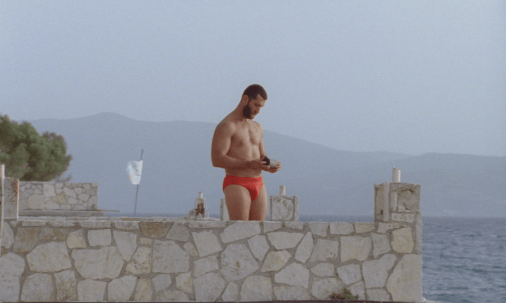 Man in a red swimsuit overlooking the Mediterranean in A King, Gazing at the Sea