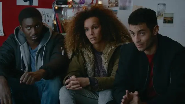 Three characters from Woke sitting together in a scene from the French LGBTQ+ series, now streaming on Dekkoo.