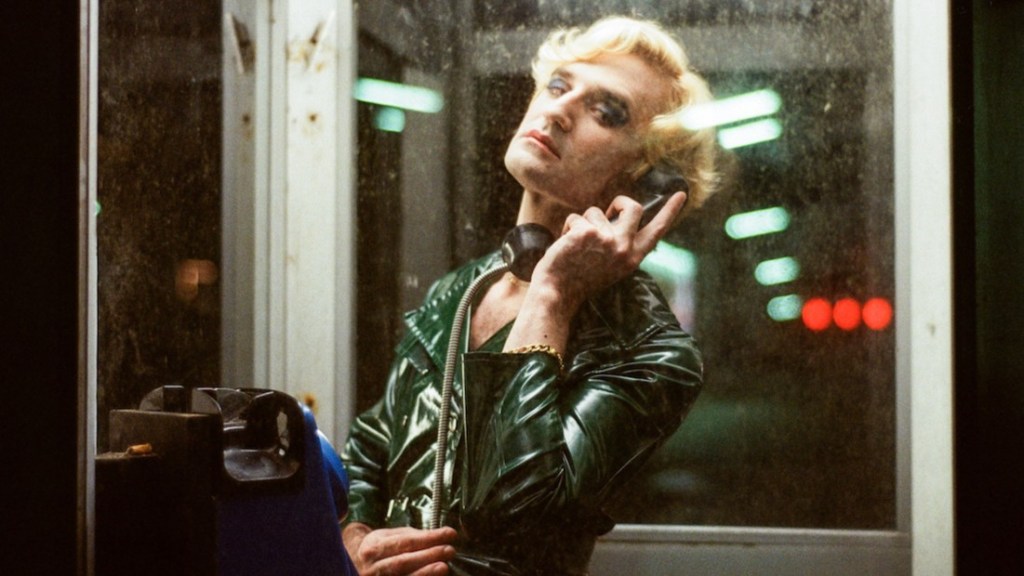 Knife + Heart film still featuring a blond man in a phone booth, from the queer horror movie streaming on Dekkoo