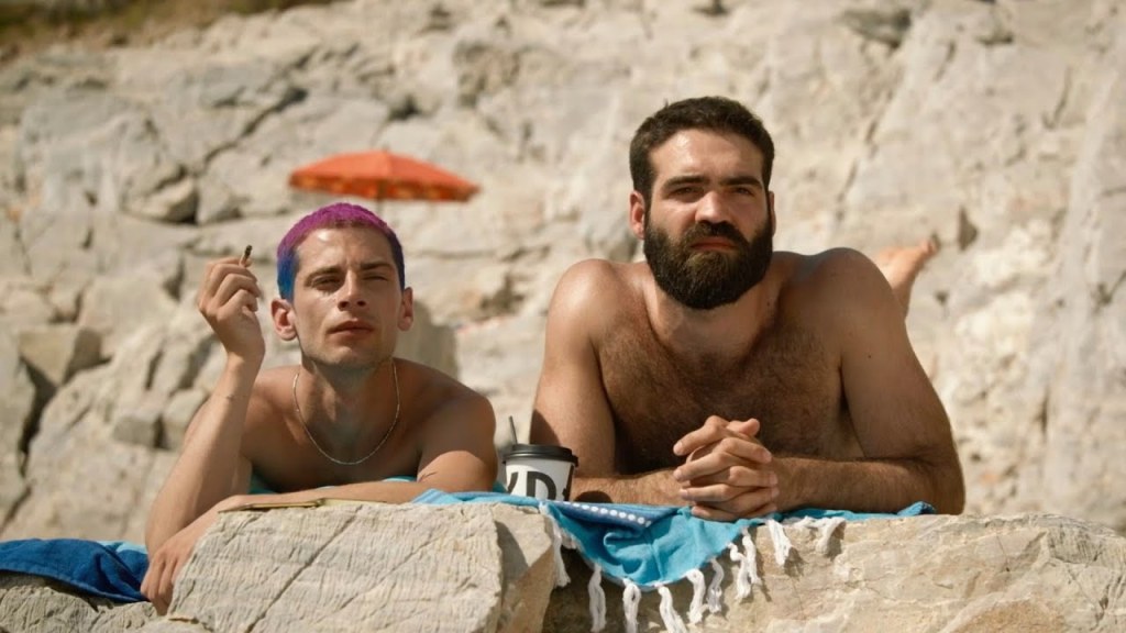 Two men relaxing on a beach in The Summer With Carmen, a gay film streaming on Dekkoo