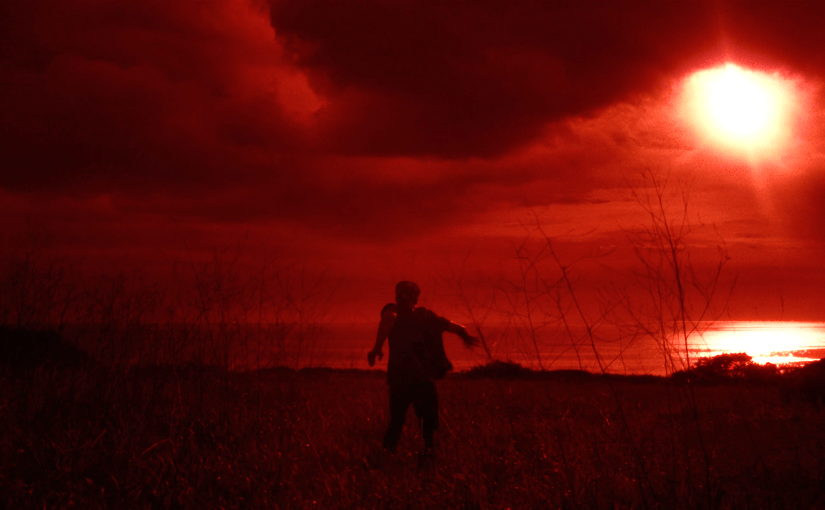 Scorch Marks queer horror film with a lone man beneath a fiery red apocalyptic sky